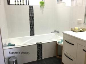 een badkamer met een bad en een wastafel bij Bowen Sunrise Retreat Homestay in Bowen