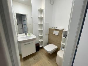 Baño blanco con lavabo y aseo en New Stylish City Center Apartment, en Komárno