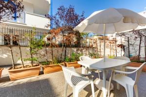 a white table and chairs with an umbrella and potted plants at Appartamento Minerva int1 - MyHo Casa in Tortoreto Lido