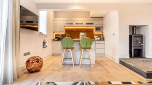 a kitchen with two green chairs in front of a counter at The Small House at The Heaning Estate in Windermere +35 photos