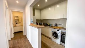 a kitchen with white cabinets and a washer at São Miguel Charming House by LFC Apts in Ponta Delgada