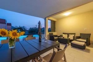 Una mesa de comedor con un jarrón de girasoles en una sala de estar. en Villa Paloma with pool, en Sukošan