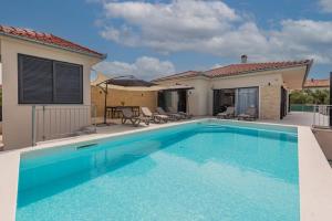 a swimming pool in front of a house at Villa Paloma with pool in Sukošan
