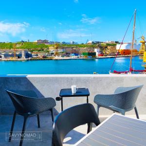 una mesa y sillas con vistas al puerto en Cabin 4 Savynomad Harbour Residences wow Views, en Cospicua