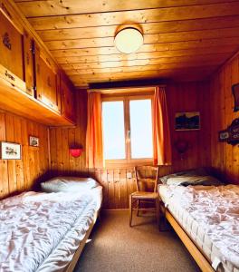 um quarto com duas camas e uma cadeira. em Chalet Tobeleck - CharmingStay em Flumserberg
