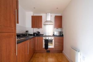 a kitchen with wooden cabinets and a stove top oven at The Zenith: Your Urban Oasis in Leicester