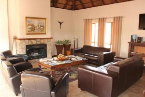 sala de estar con muebles de cuero y chimenea en 7th Hole Golf Lodge en Modimolle