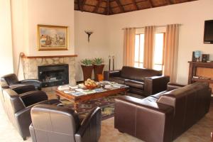 a living room with leather furniture and a fireplace at 7th Hole Golf Lodge in Modimolle