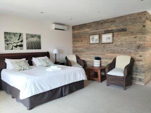 a bedroom with a large bed and two chairs at 7th Hole Golf Lodge in Modimolle