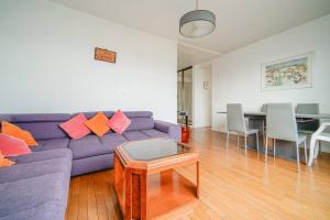 a living room with a purple couch and a table at Appartement spacieux 17ème arrondissement - II in Paris
