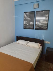 a bed in a blue room with two windows at Cherry blossom guest house in Arpora