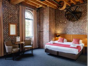 a bedroom with a large bed and a brick wall at Ghent River Hotel in Ghent