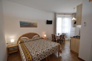a bedroom with a bed and a kitchen with a table at Appartamenti Olivo - 100 mt dal mare con aria condizionata in Marina di Campo