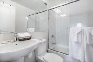 a white bathroom with a sink and a toilet and a shower at Newly Renovated 3 Bedroom Apartment in New York