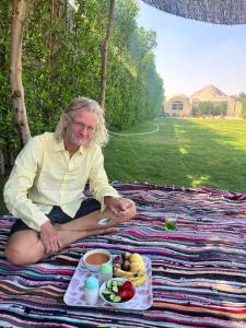 a woman sitting on a picnic blanket with a plate of food at Sahure Pyramid View Inn in Cairo +37 photos