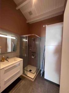 uma casa de banho com uma cabina de duche em vidro e um lavatório. em Maison rénovée - draps inclus - 700m plage em Barbâtre