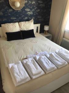 uma cama branca com quatro toalhas brancas em Maison rénovée - draps inclus - 700m plage em Barbâtre