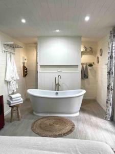 La salle de bains est pourvue d'une baignoire blanche et d'un tapis. dans l'établissement La Roulotte du Manoir 1900, à La Ferté-Gaucher