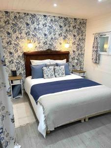 - une chambre dotée d'un lit avec du papier peint bleu et blanc dans l'établissement La Roulotte du Manoir 1900, à La Ferté-Gaucher