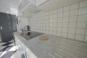 a white tiled kitchen with a counter top at Studio Didine in Charleroi