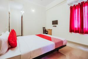 ein Schlafzimmer mit einem Bett mit roten Kissen in der Unterkunft Flagship Neknampur Near Golconda Fort in Haidar Sāhibgūda