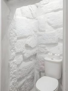 biała łazienka z toaletą i kamienną ścianą w obiekcie Serpa Beach House w mieście Matosinhos