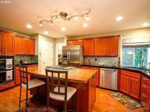 a kitchen with wooden cabinets and a island with bar stools at Forest & City Views - Near Portland, Nike & Intel in Beaverton