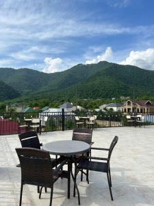 a patio with a table and chairs with mountains in the background at Gabala Boutique Hotel in Gabala