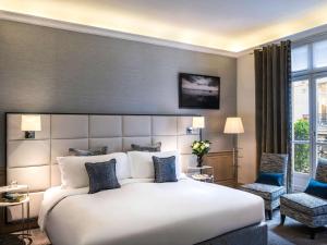 a bedroom with a large bed and a large window at Sofitel Paris Baltimore Tour Eiffel in Paris