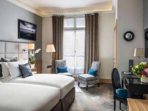 パリにあるソフィテル パリ バルティモア トゥール エッフェルのベッドとデスクが備わるホテルルームです。