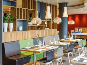 un restaurante con mesas, sillas y luces colgantes en Novotel Berlin Mitte en Berlín