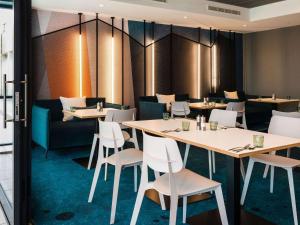 une salle à manger avec des tables et des chaises blanches dans l'établissement Ibis Christchurch, à Christchurch