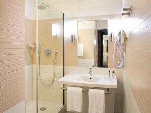 La salle de bains est pourvue d'un lavabo et d'une douche. dans l'établissement Mercure Libourne Saint Emilion, à Libourne