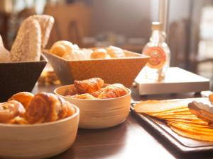 a table topped with bowls of bread and pastries at Novotel Marseille Centre Prado Vélodrome in Marseille