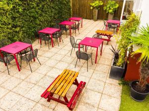 um grupo de mesas e cadeiras com mesas e bancos cor-de-rosa em ibis budget Issy Les Moulineaux Paris Ouest em Issy-les-Moulineaux