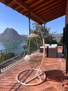 a swinging chair on a patio with a view of the water at Sweet View in Lugano