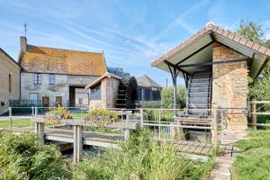 une petite maison avec une terrasse en bois devant un bâtiment dans l'établissement L'Escale du Moulin - Au coeur du Calvados, à Saint-Pierre-sur-Dives