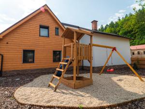 un parque infantil de madera con una escalera frente a una casa en Resort U sýrárny en Sobotín