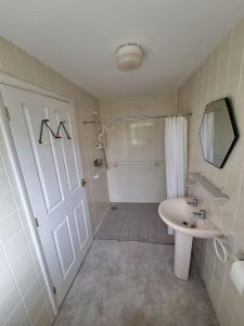 a bathroom with a shower and a sink and a white door at Elgar Escape in Barnstaple