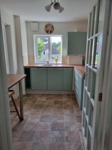 a kitchen with green cabinets and a table and a window at Elgar Escape in Barnstaple