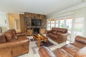 a living room with leather furniture and a fireplace at Footprints In The Sand - Kini Bay in Kini Bay