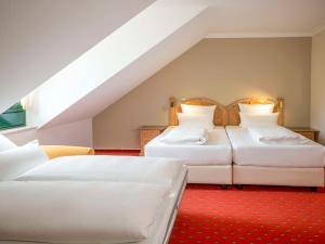 Atomis Hotel Munich Airport by Mercure في أُبردينغ: غرفة نوم بسريرين وسجادة حمراء