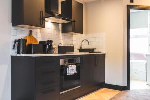 a kitchen with black cabinets and a stove at Luxury Central Derby Apartment in Derby