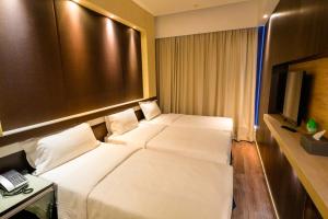 a hotel room with two beds and a television at Epoch Hotel in Hong Kong