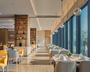 成都市にあるHyatt Place Chengdu Bio-Townのテーブルと椅子、大きな窓のあるレストラン