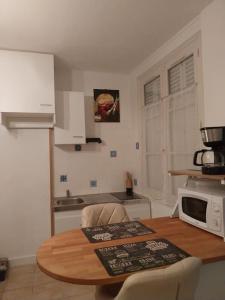 a kitchen with a wooden table and a microwave at Cocon calme, 2 pièces Tours proche bord de Loire in Tours