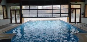 a large swimming pool in a building with windows at Charmant logement avec piscine in Bergerac