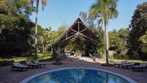 a swimming pool in front of a pavilion with palm trees at Saffron Garden Malindi in Malindi