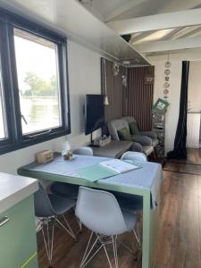 um quarto com uma mesa e cadeiras e uma sala de estar em Aangenaam op de Rijn, woonboot, inclusief privé sauna em Alphen aan den Rijn