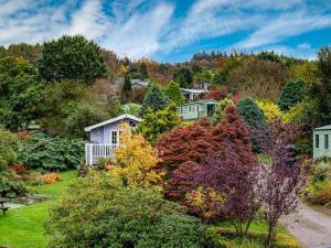 a garden with colorful trees and houses on a hill at Pass the Keys Gorgeous Home in Beautiful Kippford Country Park in Dalbeattie